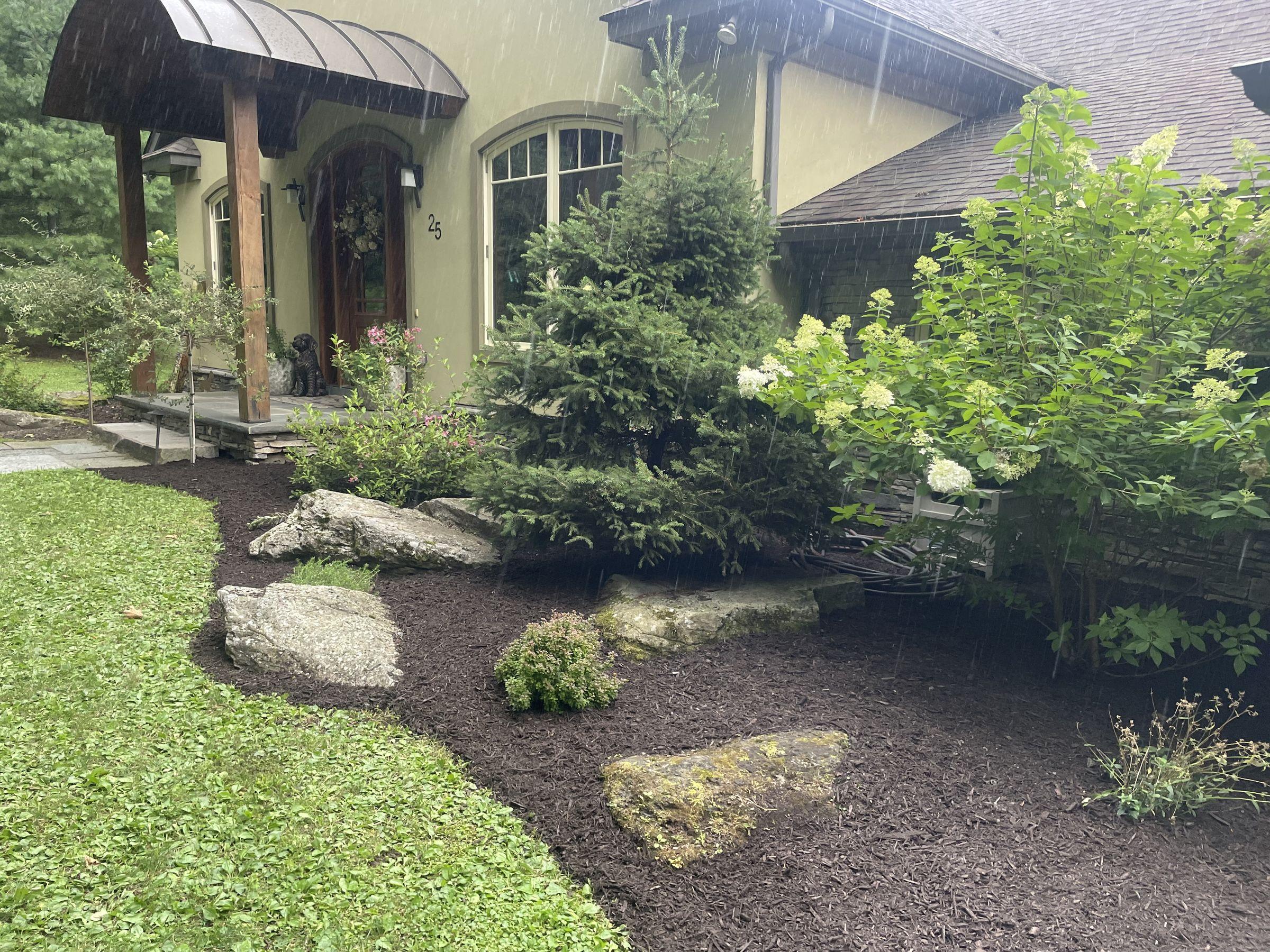 Mulched landscape bed with boulders and plantings